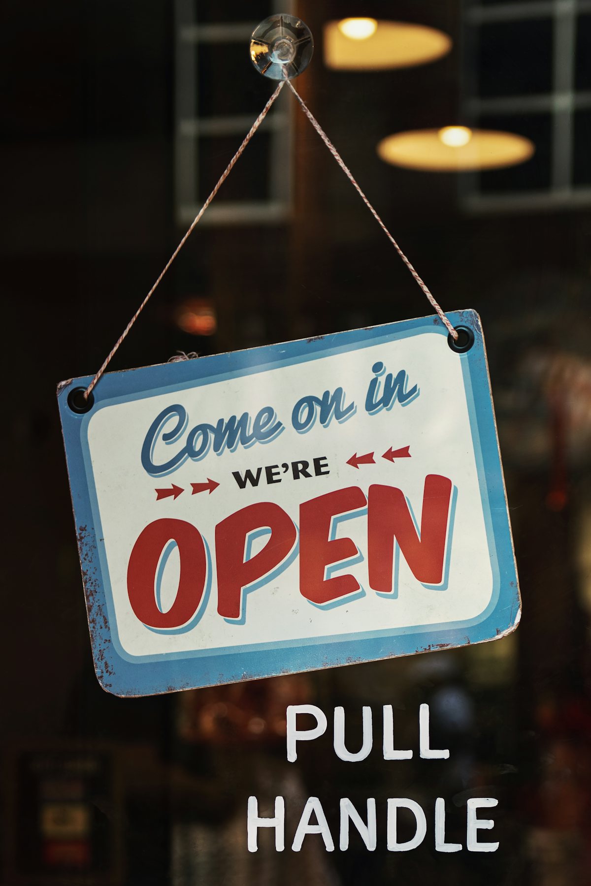 Letrero que dice Come in, we're open colgado en la puerta de un local